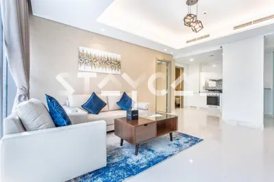 a living room with a white couch and blue pillows at Staycae Holiday Homes - Paramount Midtown in Dubai