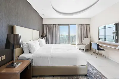 a hotel room with a bed and a desk at ALiving Elegant 1BR I Burj Khalifa View I Paramount Towers- 6103 in Dubai