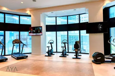 a gym with exercise bikes in a room with windows at Jumeirah Gate Tower 1 - Stylish Apartment with Pool & City Views By ĀYA Boutique in Dubai