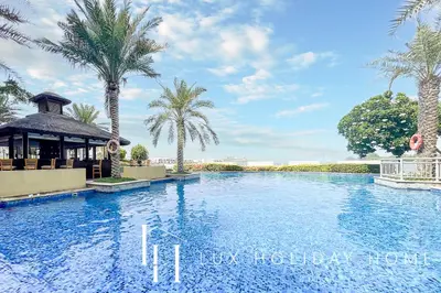 a swimming pool with palm trees and a gazebo at LUX - The Shoreline Penthouse Suite in Dubai