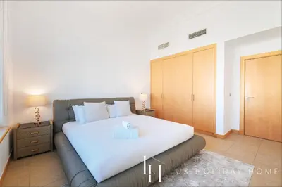 a bedroom with a large white bed and a wooden closet at LUX - The Shoreline Penthouse Suite in Dubai