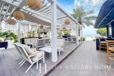 a patio with chairs and tables and the ocean at LUX - The Shoreline Penthouse Suite in Dubai