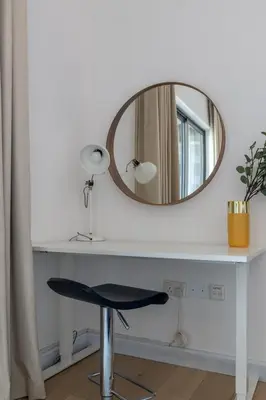 a mirror sitting on top of a white desk with a stool at GuestReady - Upscale Modern Apt in Downtown in Dubai