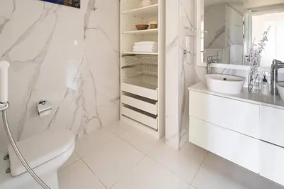 a white bathroom with a toilet and a sink at Frank Porter - Fairmont Residence South in Dubai