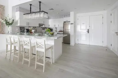 a kitchen with a large white island with white stools at Frank Porter - Fairmont Residence South in Dubai