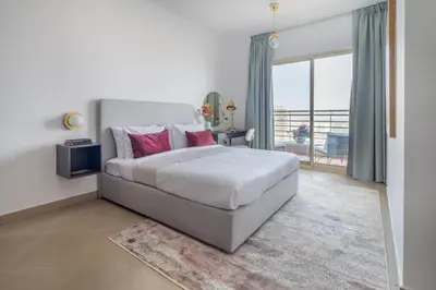 a bedroom with a bed with pink pillows and a balcony at Frank Porter - Icon Tower 1 in Dubai