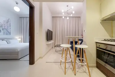 a bedroom with a bed and a kitchen with stools at Alluring 1 BD Apartment in Business Bay with Burj Khalifa view in Dubai