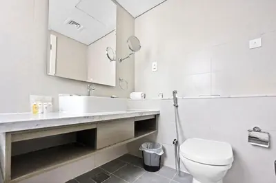 a bathroom with a toilet and a sink and a mirror at ALiving Modern 1BR Apartment with Balcony & Canal View I DAMAC Maison Prive A- 517 in Dubai