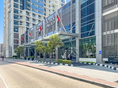 a street in front of a building with palm trees at ALiving Modern 1BR Apartment with Balcony & Canal View I DAMAC Maison Prive A- 517 in Dubai