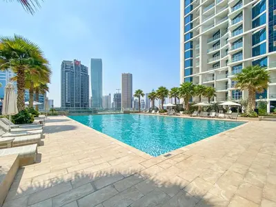 a swimming pool with palm trees and a tall building at ALiving Modern 1BR Apartment with Balcony & Canal View I DAMAC Maison Prive A- 517 in Dubai