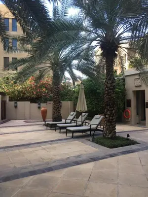 a group of palm trees with chairs and an umbrella at Burj Dubai Area - 5min Walk - Luxury 2 Bedroom Apartment in Dubai