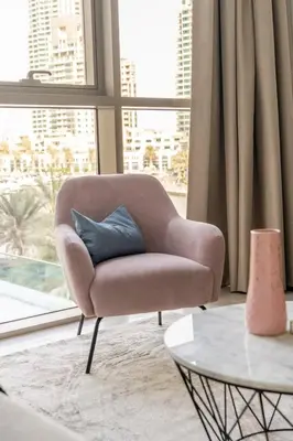 a chair with a blue pillow in a living room at GuestReady - Deluxe Waterfront View in the Marina in Dubai