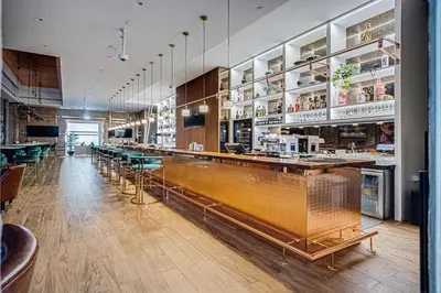 a restaurant with a long bar with green chairs at Luxury 2 Bedroom in Paramount Midtown Residence in Dubai