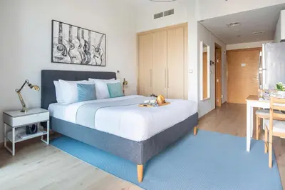 a bedroom with a large bed with a blue rug at Frank Porter - Azizi Aura in Dubai