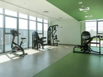 a gym with several tread machines in a room with windows at Frank Porter - Azizi Aura in Dubai