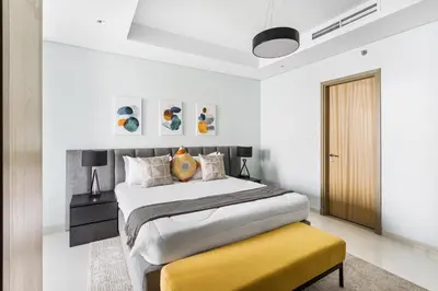 a bedroom with a large bed and a yellow bench at ALiving Luxe 2BR with higest Infinity Pool Close to Dubai Mall & Burj Khalifa in Dubai