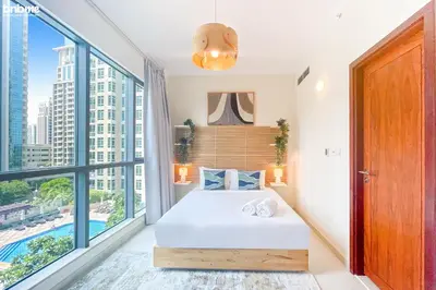 a bedroom with a bed and a large window at bnbme - Luxury 2BR Near Burj Khalifa Apt Balcony Pool Gym Concierge Near Dubai Mall in Dubai