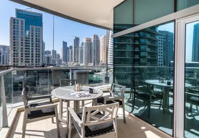a balcony with tables and chairs and a view of the city at The Smart Concierge - Marina Scape in Dubai