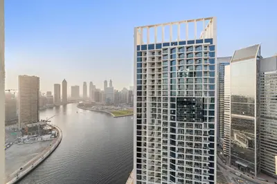 a tall building next to a river in a city at ALiving Luxury Studio with Canal Views I DAMAC Maison Prive 2512 in Dubai
