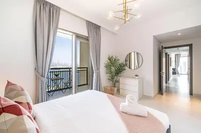 a white bedroom with a large bed and a balcony at Panoramic Burj Views - Lovely 3BR in Creek Harbour in Dubai