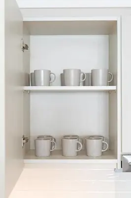 a row of cups on shelves in a kitchen at Panoramic Burj Views - Lovely 3BR in Creek Harbour in Dubai