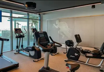 a gym with several exercise bikes and a large window at Lovely 1 BD apartment in Beach Vista Tower in Dubai