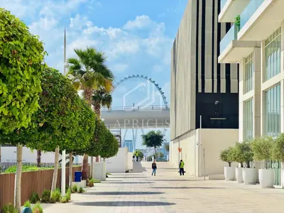 a walkway with a ferris wheel in the background at Lovely 1 BD apartment in Beach Vista Tower in Dubai