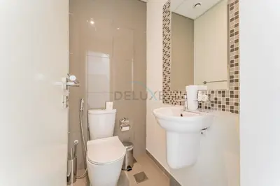 a white bathroom with a toilet and a sink at Flawless 3BR Townhouse with Assistant's Room at DAMAC Hills 2 by Deluxe Holiday Homes in Dubai