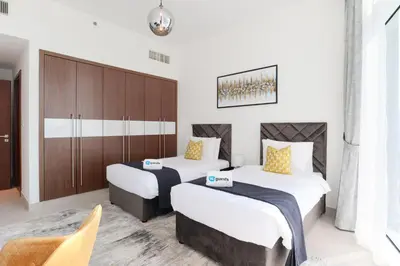 a hotel room with two beds and a cabinet at HiGuests - Spacious Apt Near Zabeel Park With Panoramic Views in Dubai