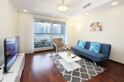 a living room with a blue couch and a tv at RH- Lovely 1BR apartment in JLT, near metro in Dubai