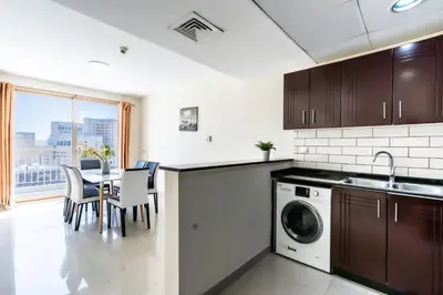 a kitchen with a washing machine and a table with chairs at RH- Bright 1BR in JVC, near Circle mall in Dubai