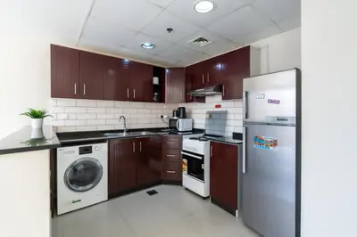 a kitchen with a refrigerator and a washer and dryer at RH- Bright 1BR in JVC, near Circle mall in Dubai