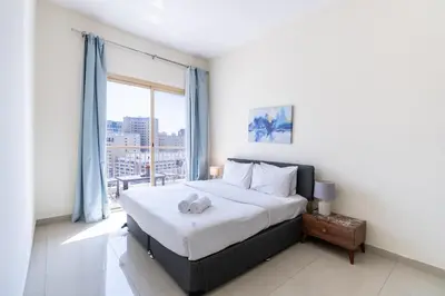 a bedroom with a bed and a large window at RH- Bright 1BR in JVC, near Circle mall in Dubai