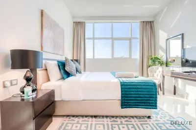 a bedroom with a large bed and a desk at Intimate Studio in Damac Ghalia Jumeirah Village Circle by Deluxe Holiday Homes in Dubai