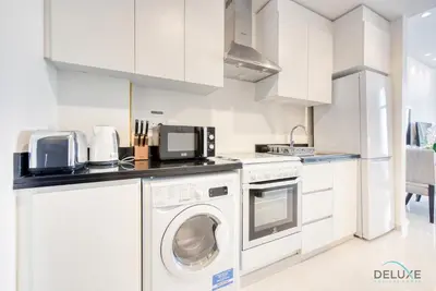 a white kitchen with a washer and dryer at Peaceful Studio at Celestia A Dubai South by Deluxe Holiday Homes in Dubai