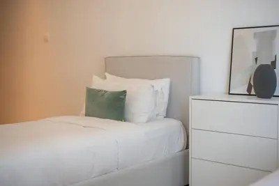 a white bed with a green pillow and a dresser at Astonishing 3BDR in the heart of Dubai Marina in Dubai