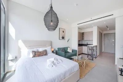 a bedroom with a white bed and a living room at Fantastic Studio resort style facilities - OFFER in Dubai