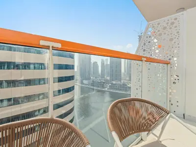 a balcony with two chairs and a view of the city at Cozy Retreat 1Bedroom on the Business Bay Canal by Suiteable Interiors in Dubai