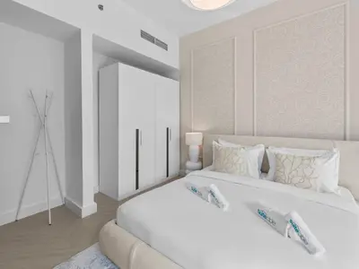 a white bedroom with a large white bed with pillows at Cozy Retreat 1Bedroom on the Business Bay Canal by Suiteable Interiors in Dubai