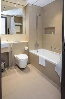 a bathroom with a tub and a toilet and a sink at Azur Regency Hotel Apartments in Dubai