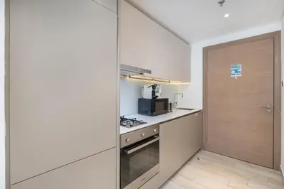 a kitchen with a door leading into a kitchen with a microwave at Unique loft with smart working station in Dubai