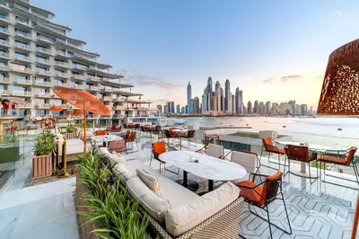 a balcony with tables and chairs and a view of the city at Private Pool Apt. Five Palm Jumeirah up to 6guest in Dubai