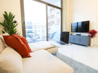 a living room with a white couch and a laptop at Elite LUX Holiday Homes - Modern Style Studio Superior Facilities in Arjan Dubai in Dubai