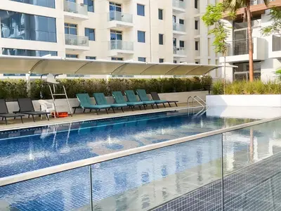 a swimming pool with blue chairs next to a building at Elite LUX Holiday Homes - Modern Style Studio Superior Facilities in Arjan Dubai in Dubai
