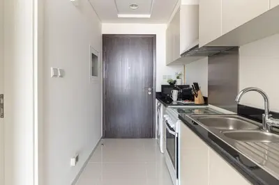 a white kitchen with a sink and a door at Frank Porter - Carson Tower C in Dubai