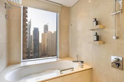 a bathroom with a tub and a large window at Daniels 1BR at JW Marriott with Dubai Marina View in Dubai