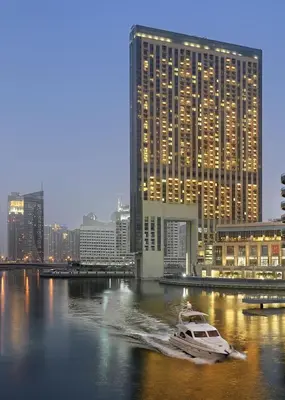 a boat in the water in front of a large building at Daniels 1BR at JW Marriott with Dubai Marina View in Dubai