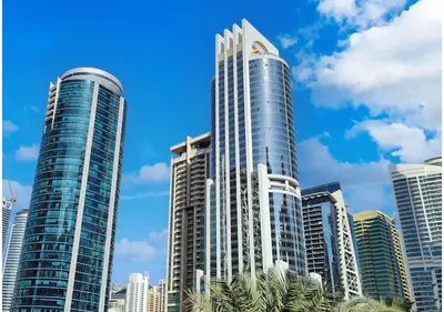 a group of tall buildings with palm trees in front at Cosmos Living Modern Studio Near Dubai Marina in Dubai