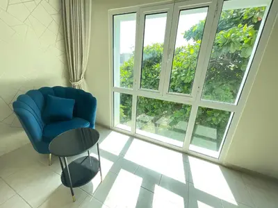 a living room with a blue chair and a large window at Discovery Gardens Haven Studios in Dubai