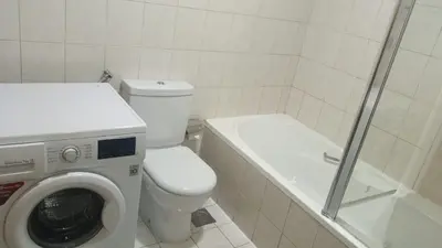 a bathroom with a toilet and a washing machine at Discovery Gardens Haven Studios in Dubai